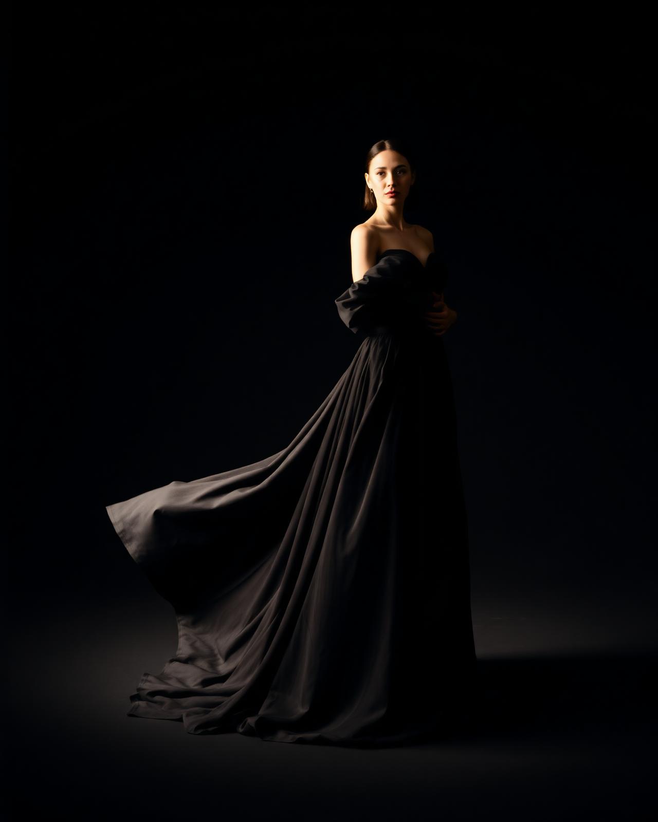 Editorial portrait in black couture against a dark studio backdrop